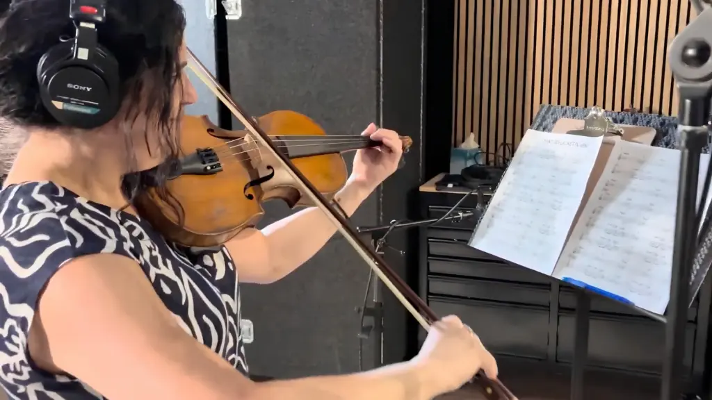 Une musicienne joue du violon devant un microphone dans un studio d'enregistrement.