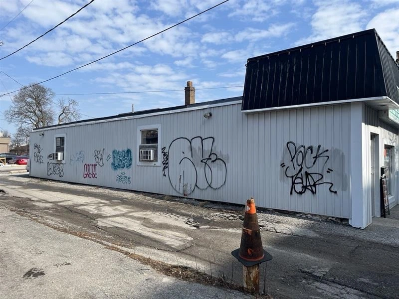White corrugated-metal exterior wall with some graffiti before painting.