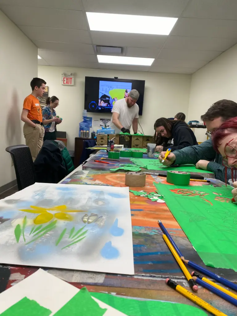 Un groupe d'élèves travaille avec concentration sur des projets artistiques dans un local.