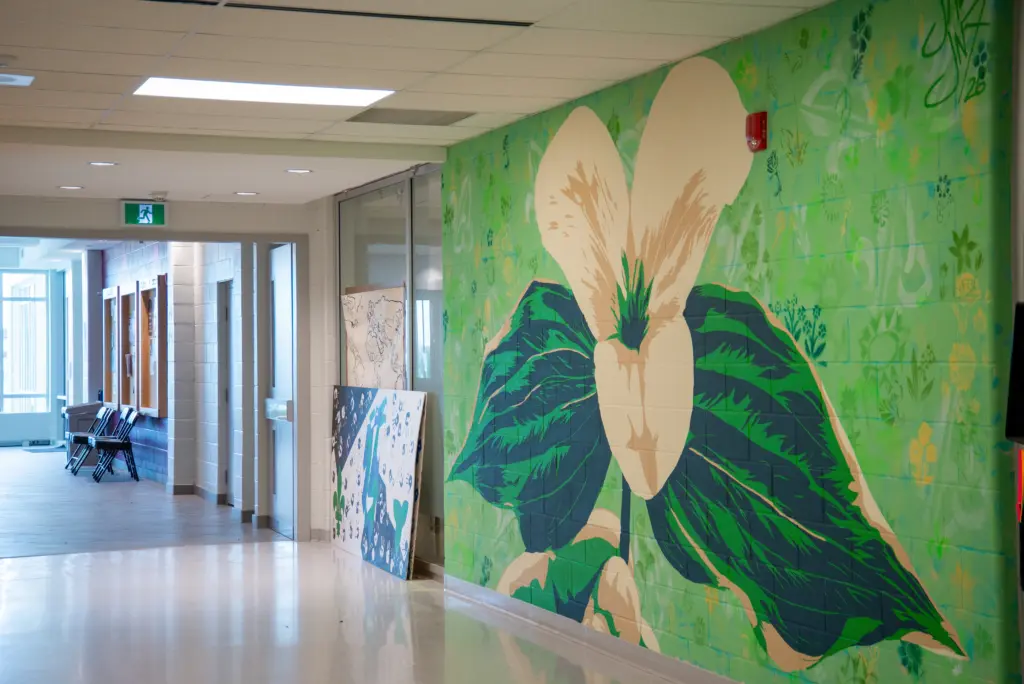 Photographie lumineuse de la murale achevée avec son trille géant dans le corridor de l'école.