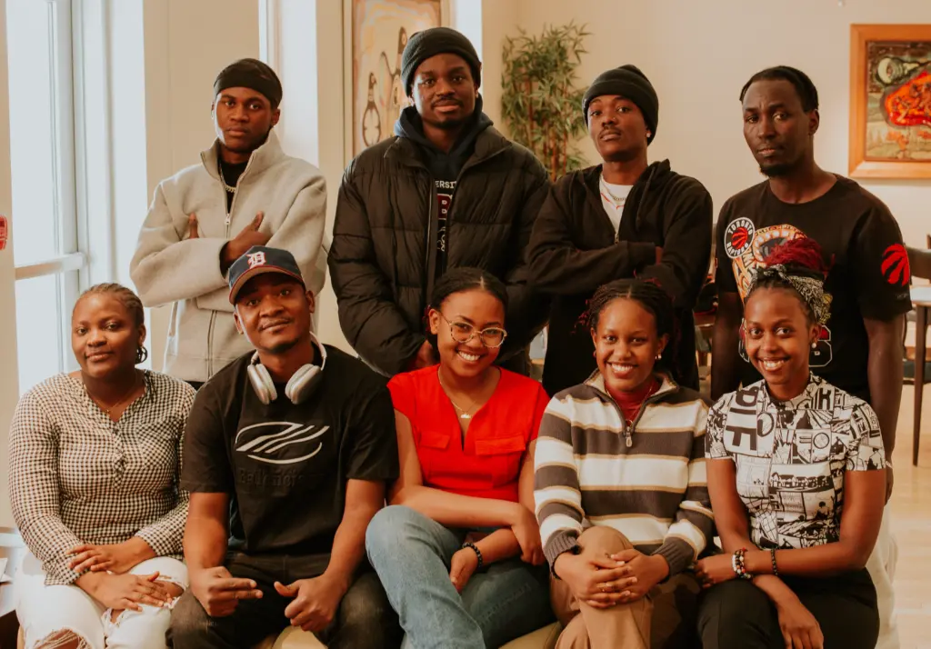 Un groupe de neuf personnes de la communauté afro-descendante et francophone posent ensemble en souriant, debout et assises.