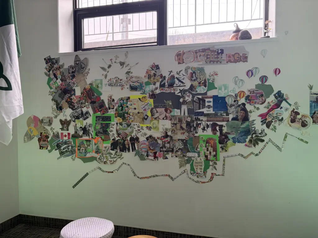 Vue large du collage mural installé sous une fenêtre, montrant la silhouette globale de l'œuvre qui s'étend sur le mur vert pâle.