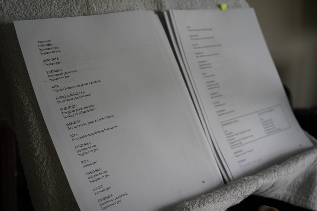 Gros plan sur un script et des partitions ouvertes sur un pupitre de musique.