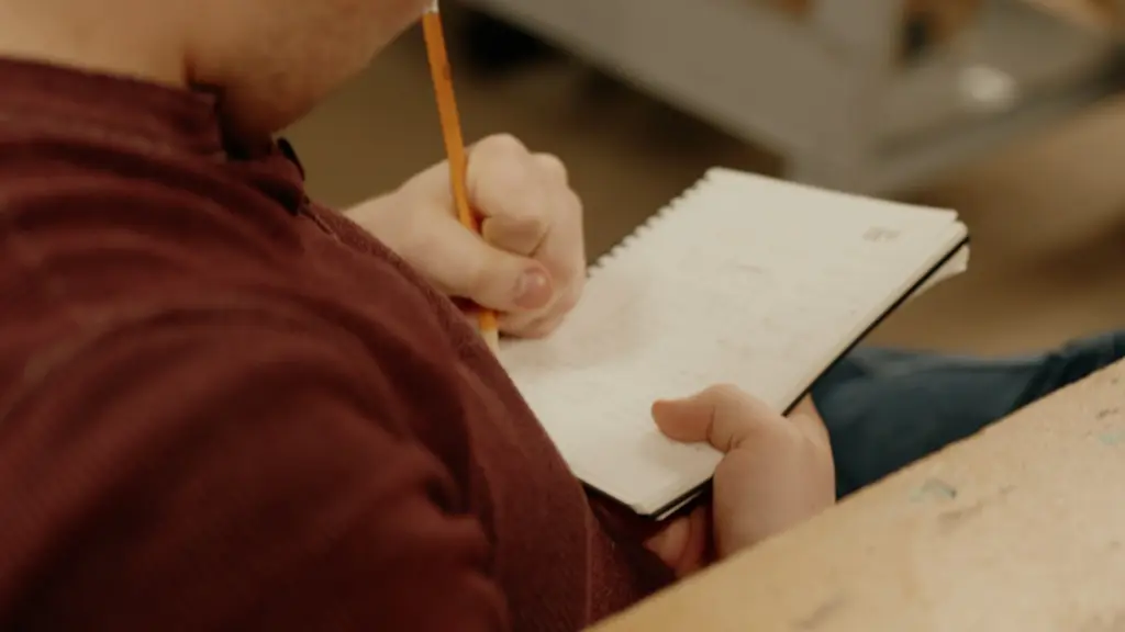 Gros plan sur la main d'une personne qui écrit des notes avec un crayon dans un carnet lors d'un atelier créatif.