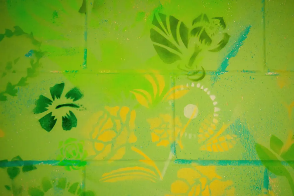 Gros plan de feuilles et de fleurs peintes en vert clair et jaune vif à l'aide de pochoirs.