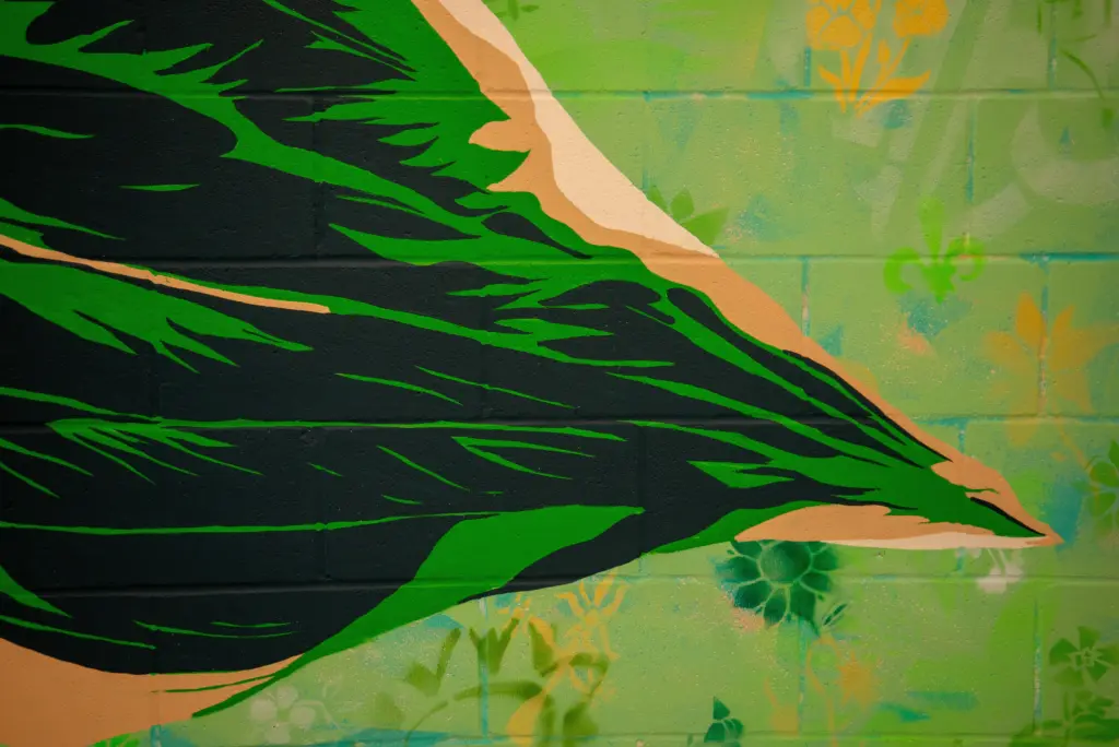 Gros plan sur les grandes feuilles vertes aux lignes dynamiques peintes au centre de la murale.