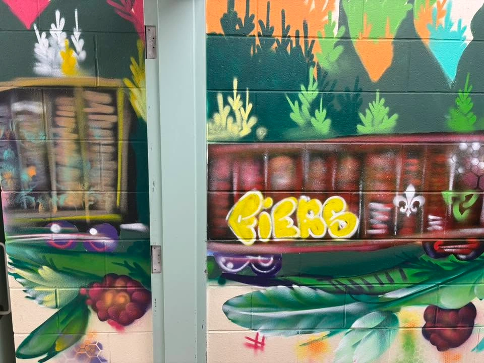 Section d’une murale intérieure montrant deux wagons de train entourés de végétation colorée. Le wagon de droite porte le mot « FIERS », une fleur de lys et un trille.