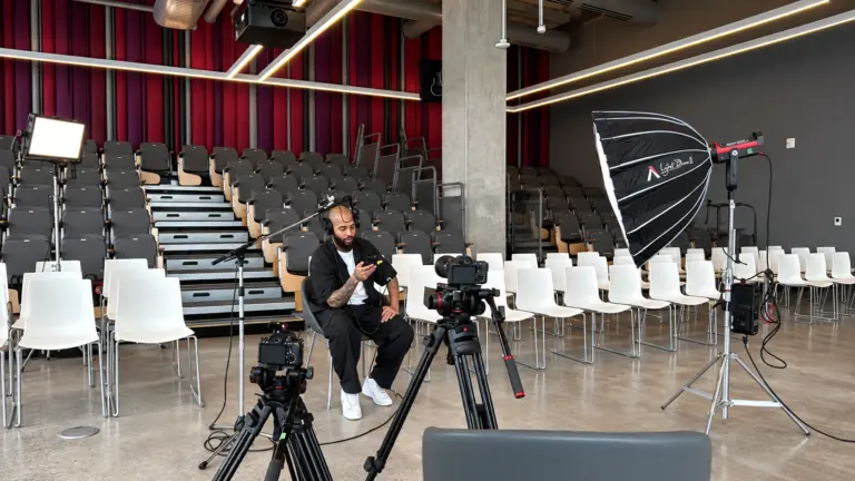 Vue d'ensemble d'un auditorium vide préparé pour une captation vidéo avec un projecteur et des trépieds.
